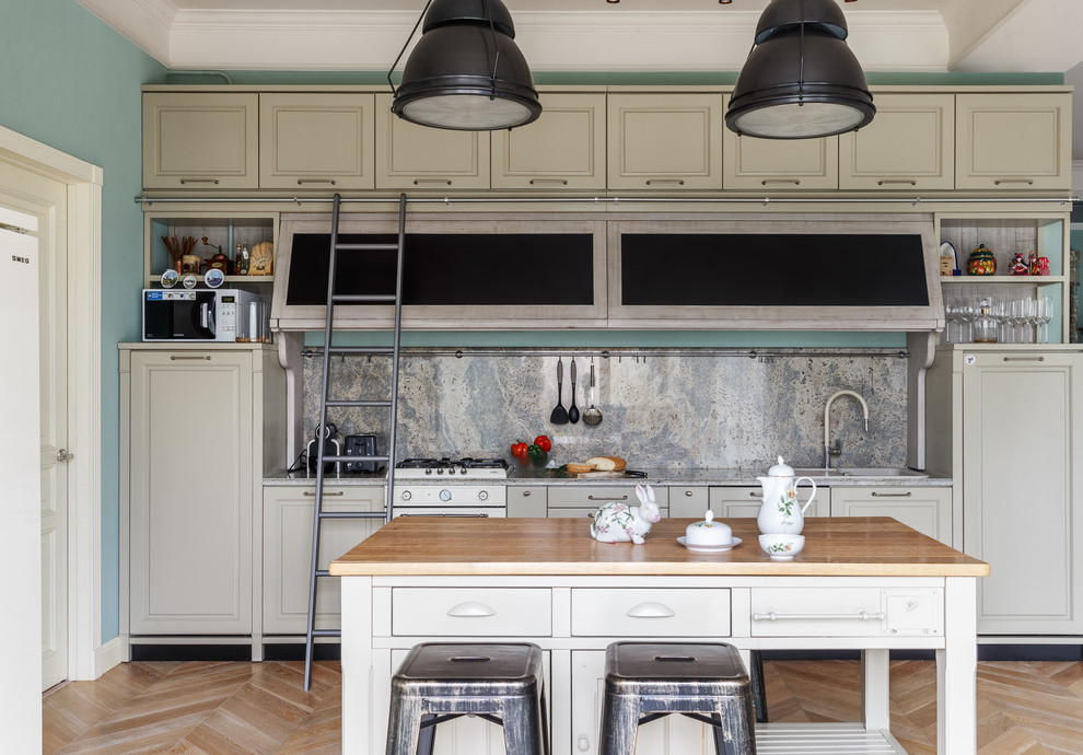 Exempel på ett klassiskt linjärt kök med öppen planlösning, med en nedsänkt diskho, luckor med upphöjd panel, grå skåp, granitbänkskiva, grått stänkskydd, stänkskydd i sten, vita vitvaror, ljust trägolv, en köksö och beiget golv