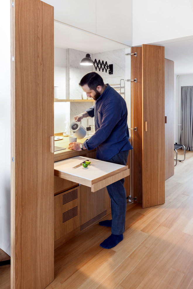 This is an example of a small contemporary enclosed kitchen in Moscow with a submerged sink, medium wood cabinets, wood worktops, white splashback, integrated appliances and medium hardwood flooring.