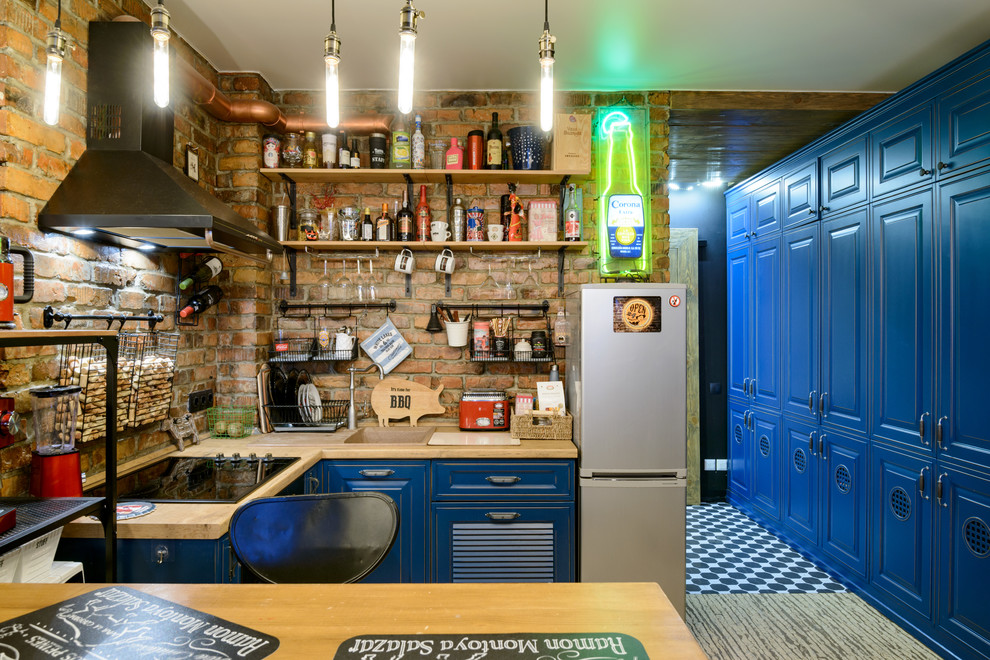 Immagine di una piccola cucina eclettica con ante blu, top in legno, paraspruzzi in mattoni, pavimento in sughero, nessuna isola, pavimento beige, top marrone, lavello da incasso, paraspruzzi marrone e ante con bugna sagomata