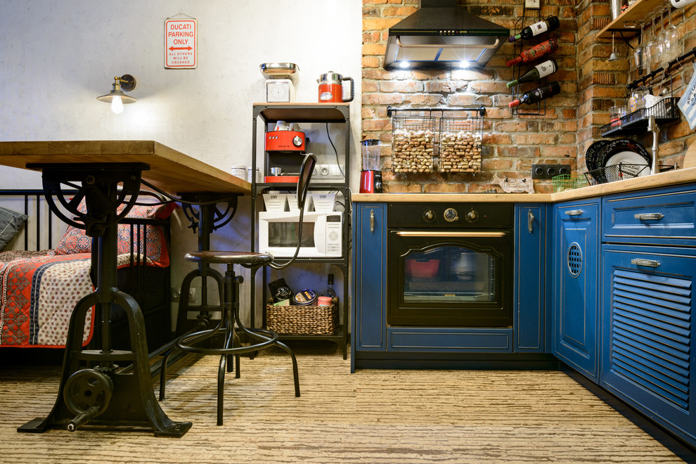 Foto på ett litet eklektiskt brun kök, med luckor med lamellpanel, blå skåp, träbänkskiva, stänkskydd i tegel, svarta vitvaror, korkgolv och beiget golv