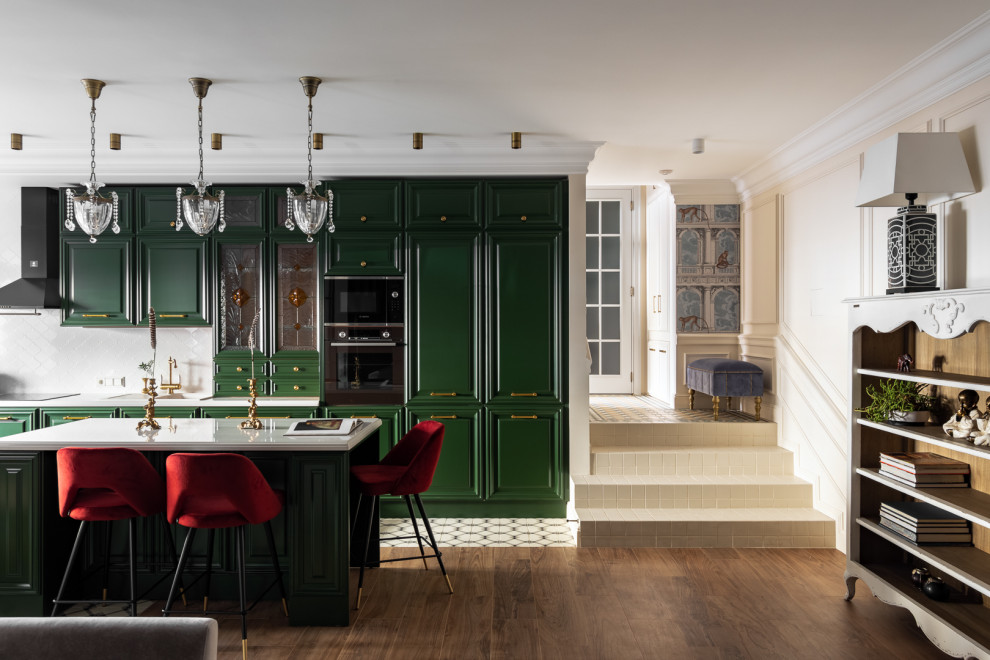 サンクトペテルブルクにあるトランジショナルスタイルのおしゃれなアイランドキッチン (レイズドパネル扉のキャビネット、緑のキャビネット、白いキッチンパネル、黒い調理設備、白いキッチンカウンター) の写真