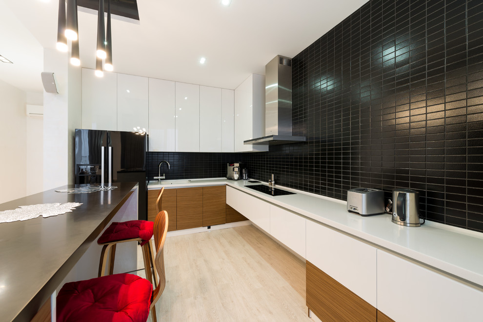 Идея дизайна: угловая кухня-гостиная в современном стиле с врезной мойкой, плоскими фасадами, черным фартуком, светлым паркетным полом, полуостровом и черно-белыми фасадами