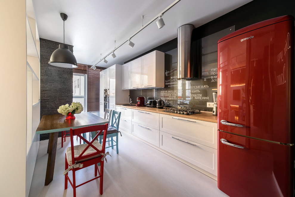 Стильный дизайн: прямая кухня-гостиная в современном стиле с накладной мойкой, белыми фасадами, черным фартуком, фартуком из стекла и серым полом без острова - последний тренд