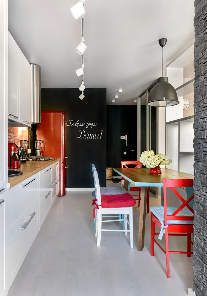 На фото: прямая кухня-гостиная в современном стиле с накладной мойкой, белыми фасадами, черным фартуком, фартуком из стекла и серым полом без острова