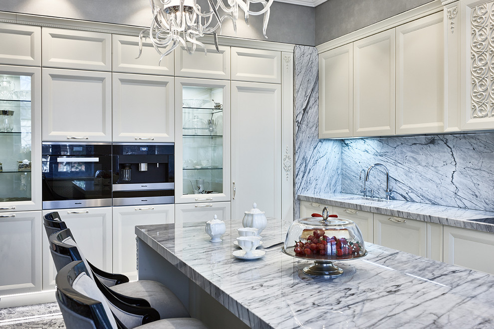 Immagine di un cucina con isola centrale chic con lavello sottopiano, ante con riquadro incassato, ante bianche e paraspruzzi grigio