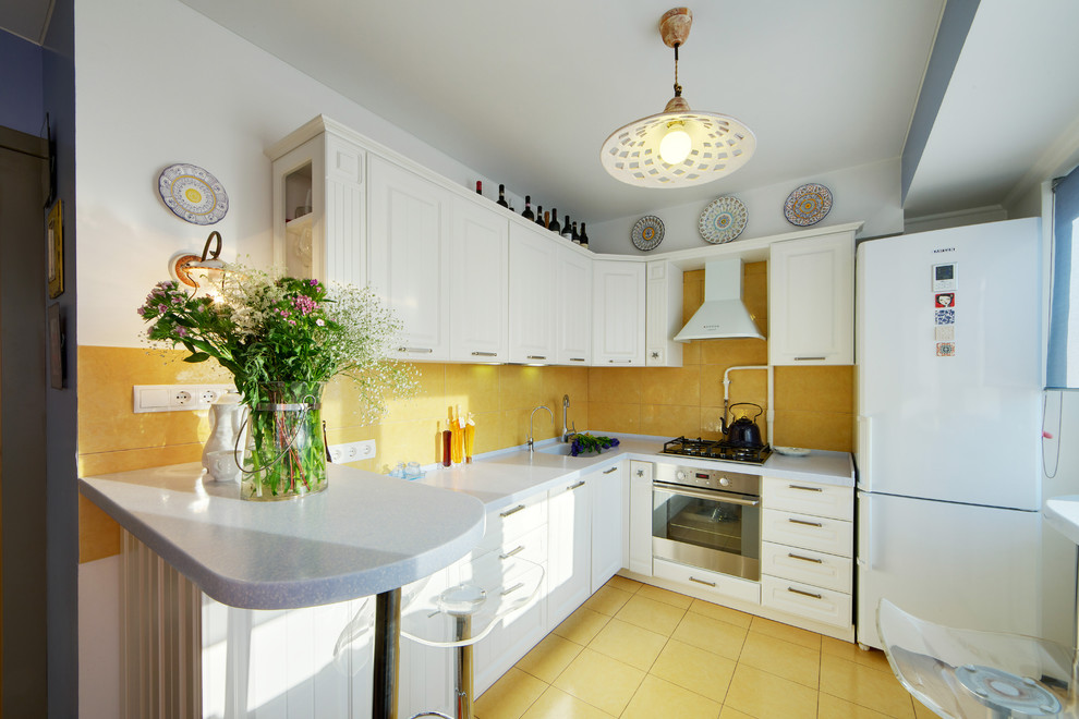 Foto de cocinas en L contemporánea abierta con puertas de armario blancas, salpicadero amarillo, electrodomésticos de acero inoxidable y suelo amarillo