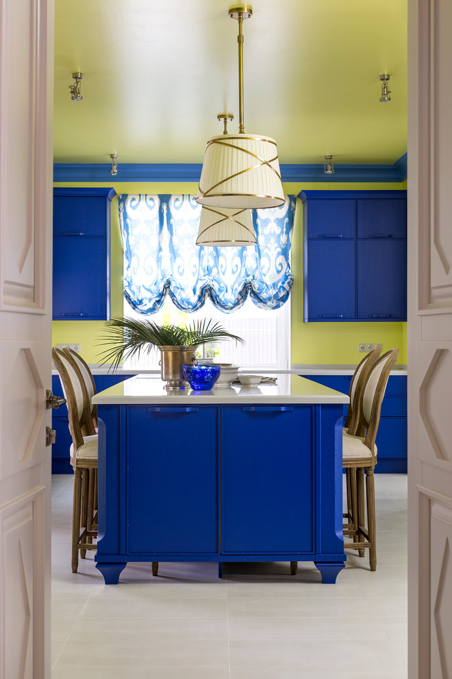 Modelo de cocina ecléctica con puertas de armario azules, salpicadero gris y una isla