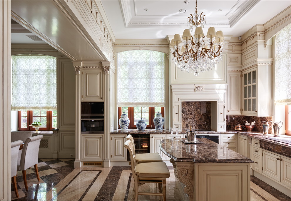 На фото: п-образная кухня в классическом стиле с белыми фасадами, коричневым фартуком, островом и коричневым полом в частном доме