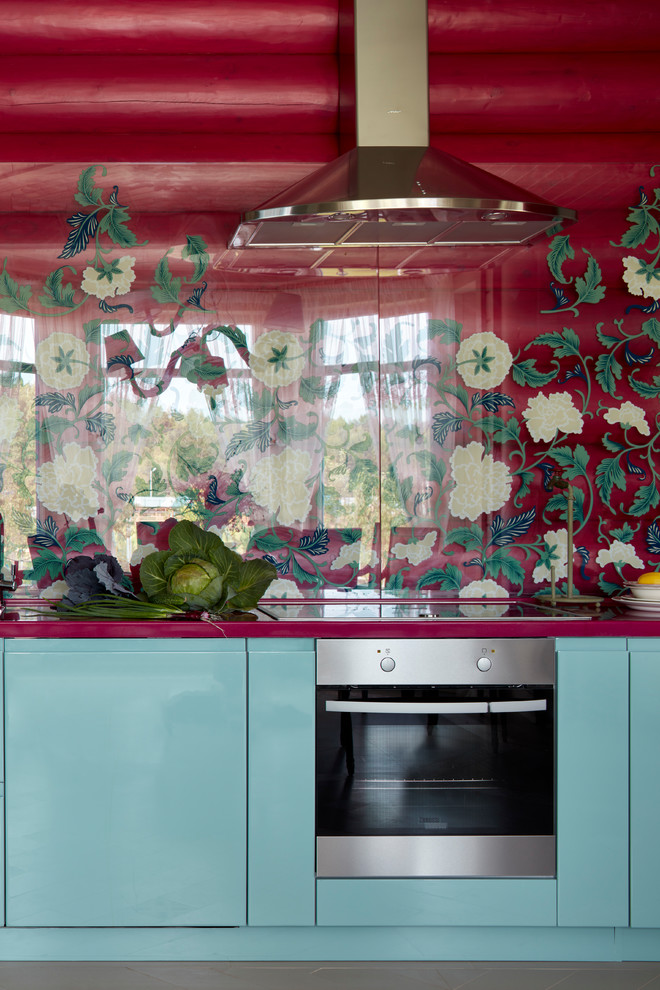 Mittelgroße Eklektische Küche mit flächenbündigen Schrankfronten, türkisfarbenen Schränken, Küchenrückwand in Rot, Glasrückwand, Küchengeräten aus Edelstahl und roter Arbeitsplatte in Moskau