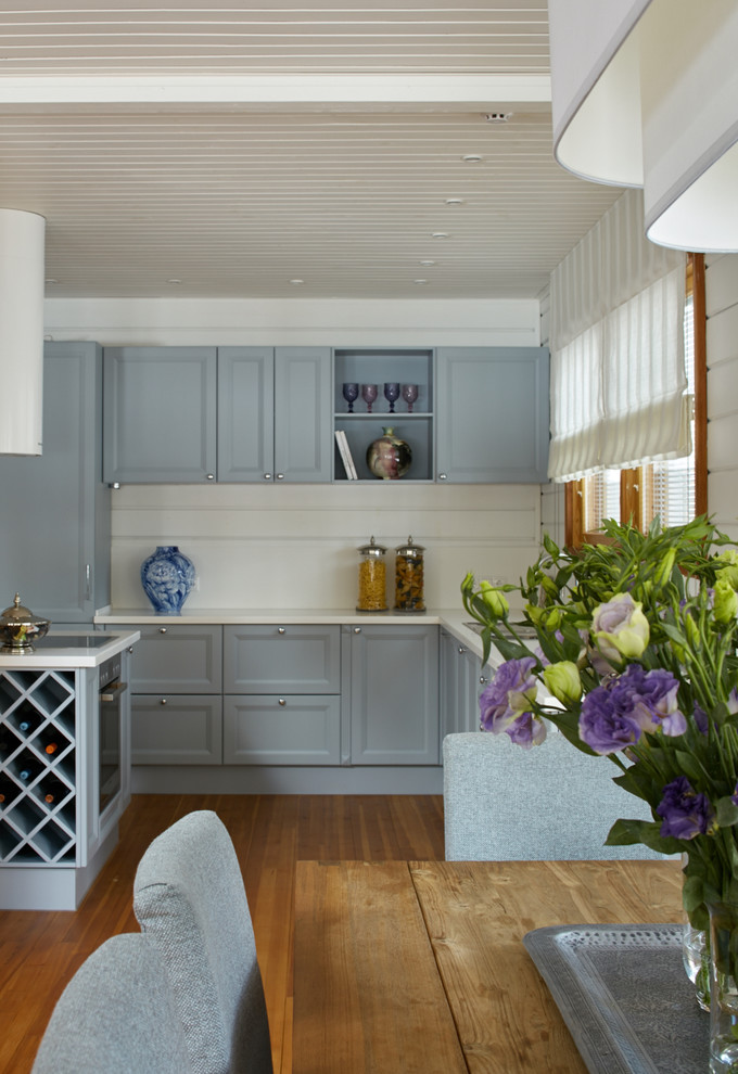 На фото: кухня в современном стиле с фасадами с утопленной филенкой, серыми фасадами, белым фартуком и паркетным полом среднего тона с