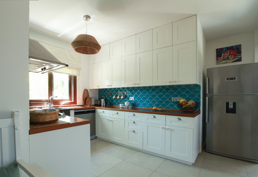 Modelo de cocina mediterránea con armarios con paneles con relieve, puertas de armario blancas, encimera de madera, suelo gris y encimeras naranjas