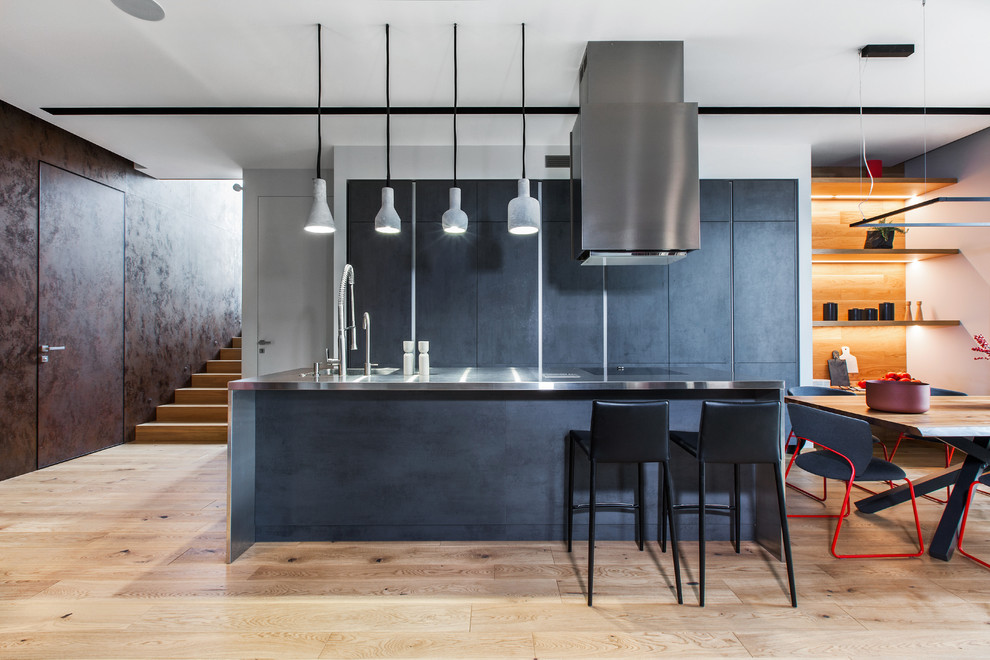 Exempel på ett stort modernt grå linjärt grått kök och matrum, med släta luckor, grå skåp, bänkskiva i rostfritt stål, en köksö, en integrerad diskho, ljust trägolv och beiget golv