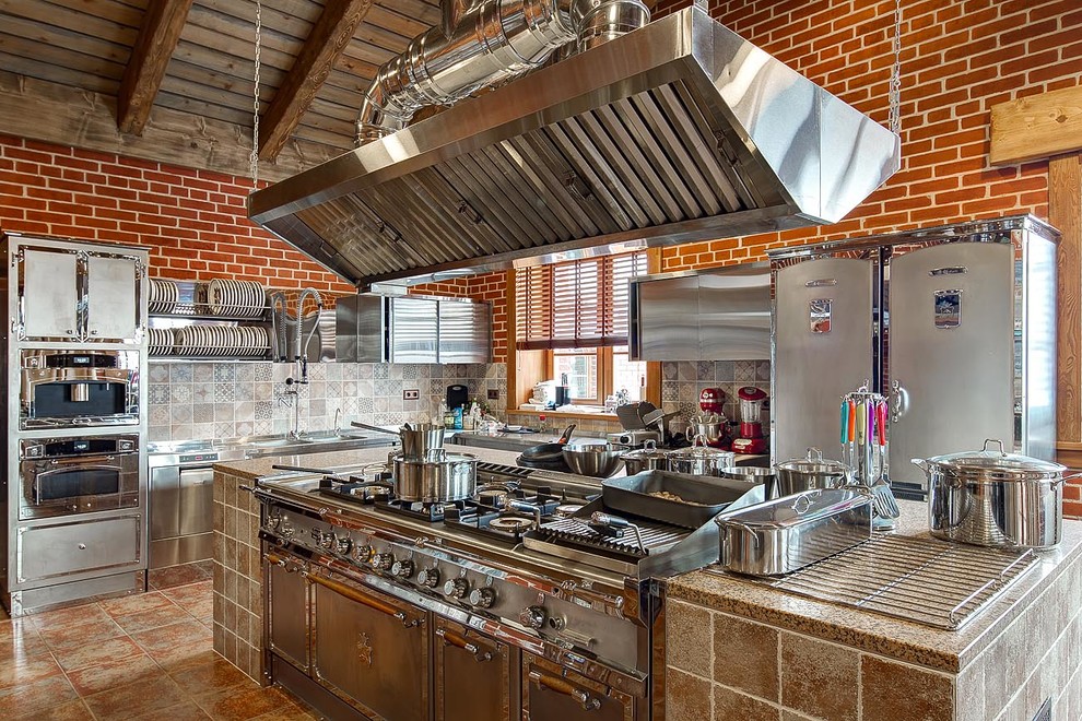 Foto på ett avskilt lantligt kök, med släta luckor, skåp i rostfritt stål, grått stänkskydd, brunt golv och rostfria vitvaror