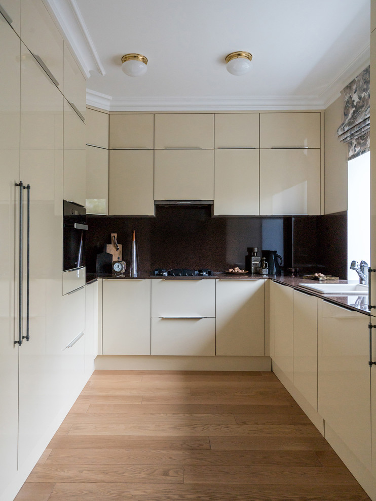 Geschlossene Moderne Küche ohne Insel in U-Form mit Einbauwaschbecken, flächenbündigen Schrankfronten, beigen Schränken, Küchenrückwand in Braun und braunem Holzboden in Moskau