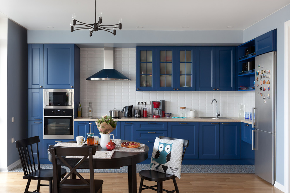 Exempel på ett mellanstort modernt kök, med en enkel diskho, blå skåp, laminatbänkskiva, vitt stänkskydd, stänkskydd i tunnelbanekakel, rostfria vitvaror, klinkergolv i porslin och skåp i shakerstil