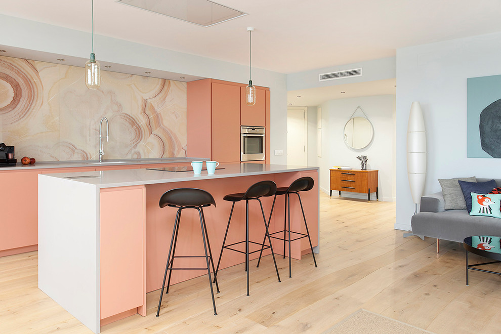Photo of a medium sized contemporary galley open plan kitchen in Barcelona with flat-panel cabinets, pink splashback, stainless steel appliances, light hardwood flooring, an island and beige floors.