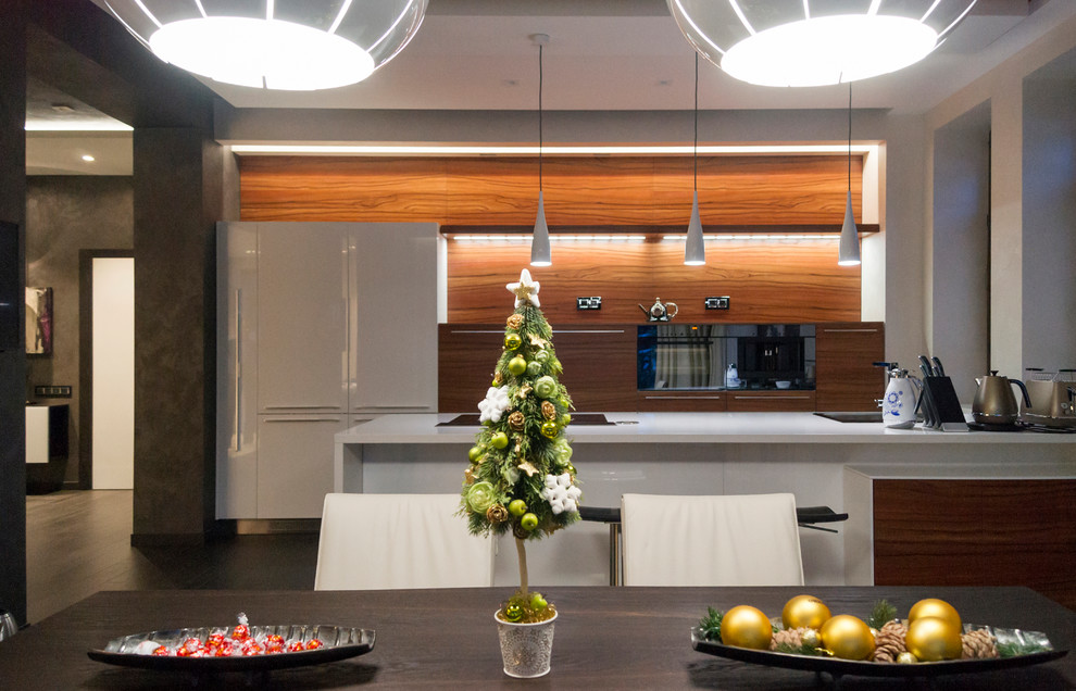 Immagine di una cucina lineare design con ante lisce, ante in legno scuro, elettrodomestici neri, penisola e top bianco