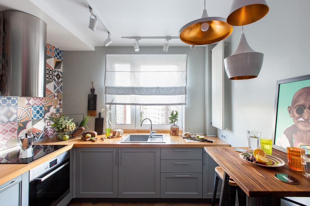 Photo of a small contemporary l-shaped enclosed kitchen in Moscow with a built-in sink, recessed-panel cabinets, grey cabinets, wood worktops, multi-coloured splashback and brown worktops.