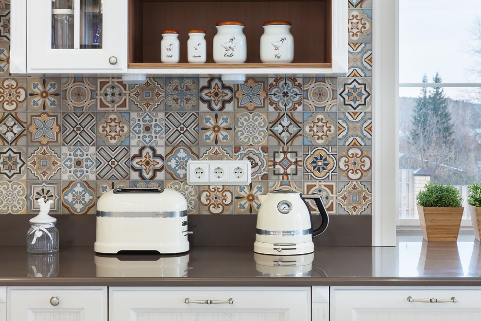 Mediterrane Küche mit Schrankfronten mit vertiefter Füllung, weißen Schränken, Mineralwerkstoff-Arbeitsplatte und Rückwand aus Keramikfliesen in Jekaterinburg