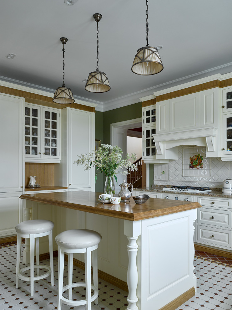 Klassisk inredning av ett avskilt, mellanstort brun brunt l-kök, med vita skåp, bänkskiva i kvartsit, vitt stänkskydd, stänkskydd i keramik, vita vitvaror, klinkergolv i keramik, en köksö, flerfärgat golv och skåp i shakerstil