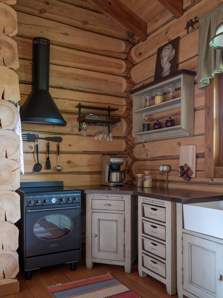 Aménagement d'une cuisine montagne avec une crédence en bois, parquet peint et un sol marron.