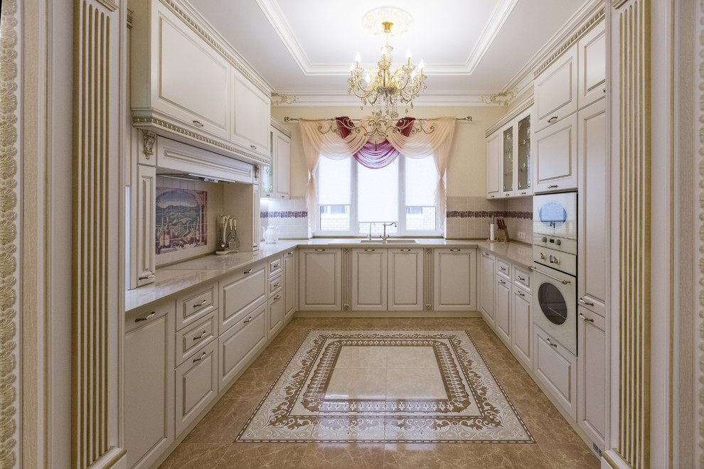 Large elegant u-shaped ceramic tile and brown floor kitchen photo in Other with a double-bowl sink, raised-panel cabinets, beige cabinets, solid surface countertops, beige backsplash, ceramic backsplash, white appliances, no island and beige countertops