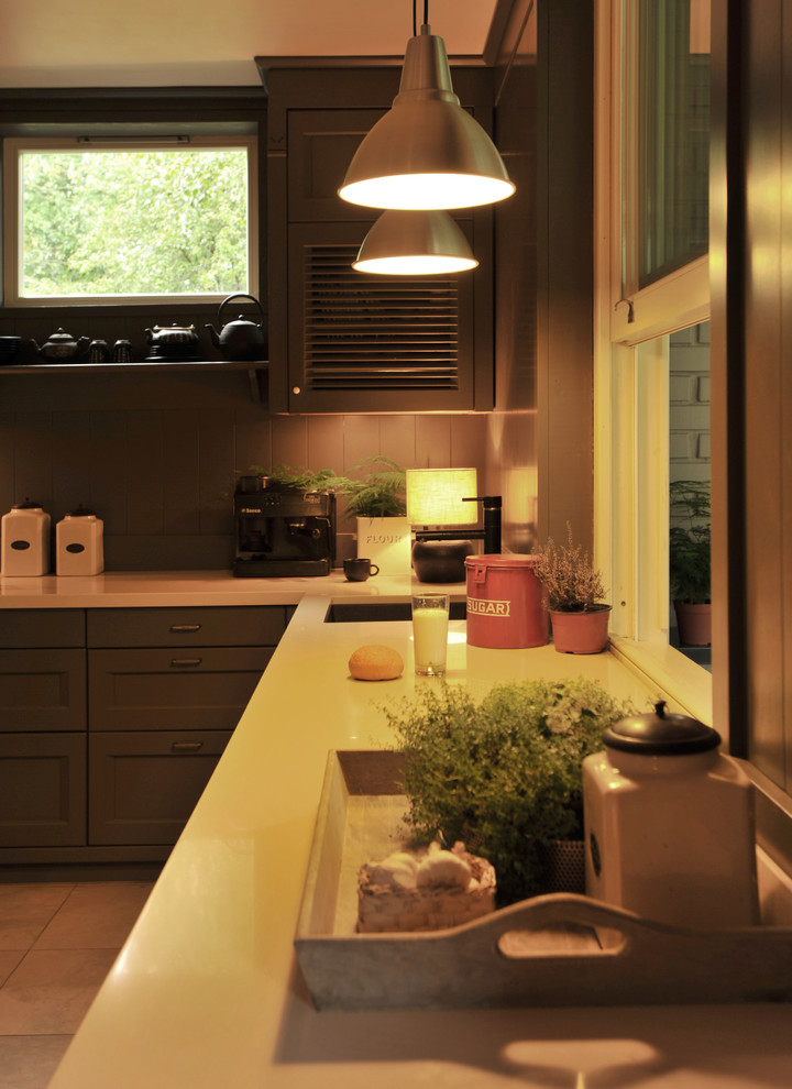 Modern inredning av ett avskilt, litet l-kök, med en undermonterad diskho, luckor med lamellpanel, grå skåp, bänkskiva i kvarts, grått stänkskydd, stänkskydd i trä, klinkergolv i keramik och grått golv