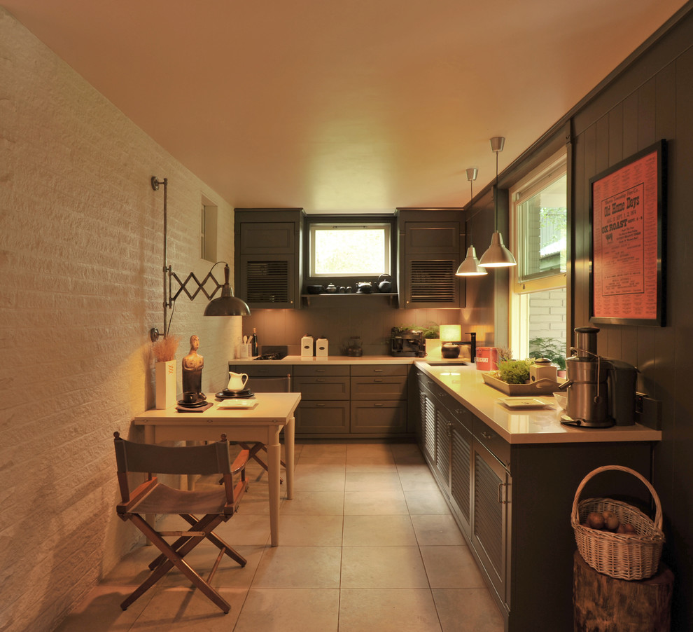 Modern inredning av ett avskilt, litet l-kök, med en undermonterad diskho, luckor med lamellpanel, grå skåp, bänkskiva i kvarts, grått stänkskydd, stänkskydd i trä, svarta vitvaror, klinkergolv i keramik och grått golv