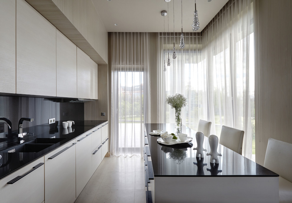 Стильный дизайн: прямая кухня в современном стиле с врезной мойкой, плоскими фасадами, белыми фасадами, черным фартуком, островом и белым полом - последний тренд