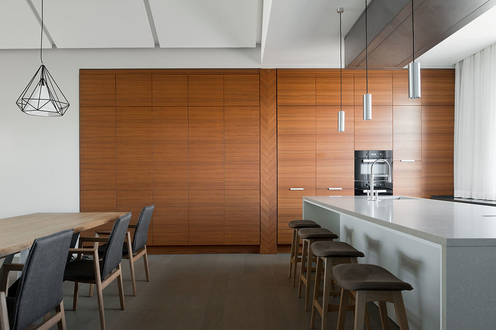 Cette photo montre une grande cuisine américaine parallèle tendance en bois brun avec un évier encastré, un placard à porte plane, plan de travail en marbre, un sol en bois brun et îlot.