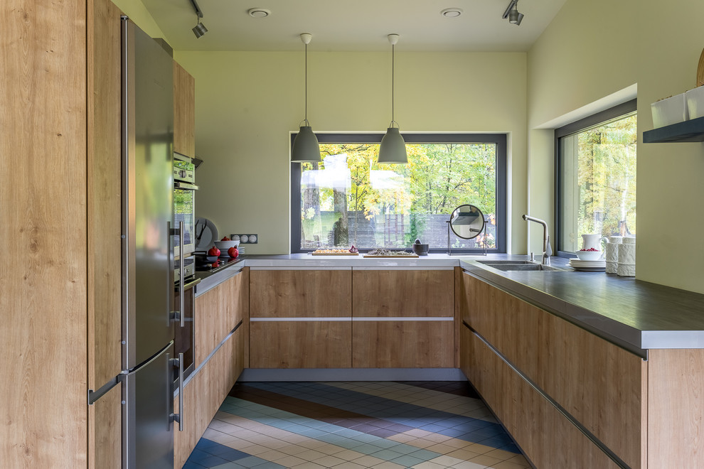 Nordisk inredning av ett mellanstort grå grått u-kök, med släta luckor, skåp i mellenmörkt trä, rostfria vitvaror, flerfärgat golv, fönster som stänkskydd och en dubbel diskho