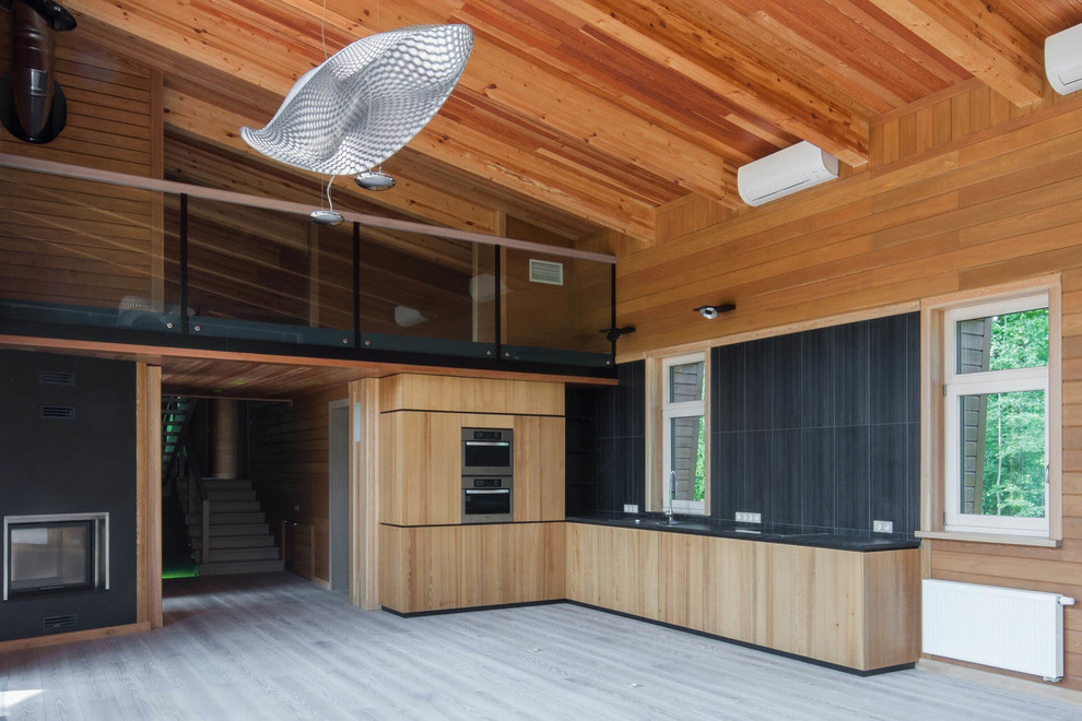 Foto de cocina contemporánea con fregadero bajoencimera, salpicadero de azulejos de piedra, electrodomésticos de acero inoxidable y suelo de madera pintada