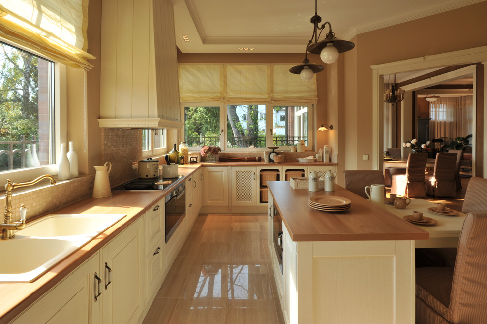 Example of a mid-sized classic l-shaped ceramic tile and beige floor enclosed kitchen design with an island, a double-bowl sink, recessed-panel cabinets, white cabinets, wood countertops, beige backsplash, mosaic tile backsplash and black appliances