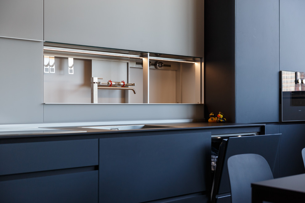 Cette image montre une cuisine design avec un évier posé, des portes de placard noires, une crédence blanche et plan de travail noir.
