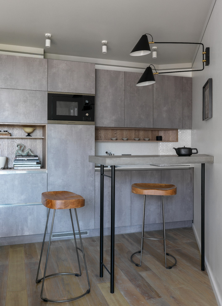 Inspiration för moderna linjära grått kök, med en nedsänkt diskho, släta luckor, grå skåp, vitt stänkskydd, svarta vitvaror och brunt golv