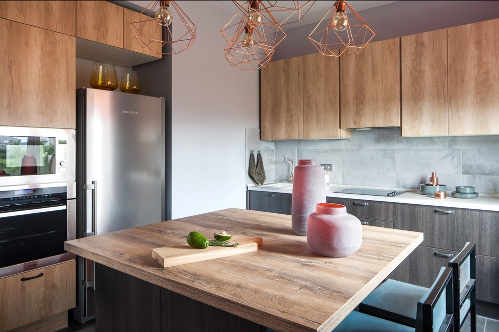 Example of a trendy l-shaped open concept kitchen design in Moscow with flat-panel cabinets, light wood cabinets, gray backsplash, stainless steel appliances, an island and brown countertops