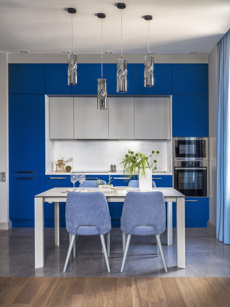 Small contemporary single-wall kitchen/diner in Moscow with a single-bowl sink, blue cabinets, composite countertops, white worktops, flat-panel cabinets, white splashback, stainless steel appliances, no island and grey floors.