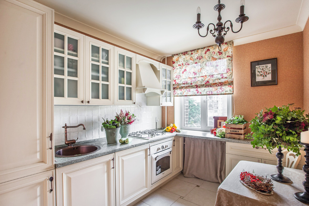 Enclosed kitchen - small cottage l-shaped ceramic tile enclosed kitchen idea in Moscow with raised-panel cabinets, beige cabinets, no island, a drop-in sink, white backsplash and white appliances