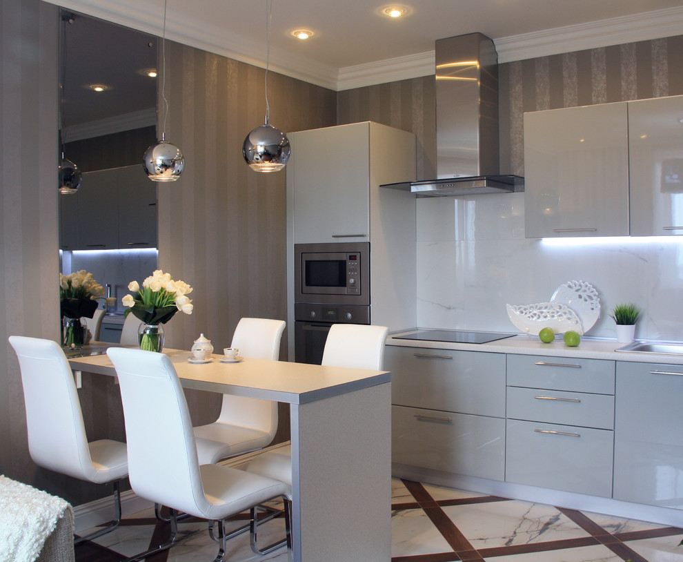 Bild på ett litet funkis linjärt kök med öppen planlösning, med en nedsänkt diskho, släta luckor, grå skåp, laminatbänkskiva, vitt stänkskydd, klinkergolv i porslin, en halv köksö och rostfria vitvaror
