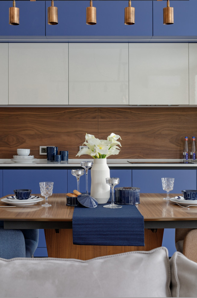 Foto på ett mellanstort funkis vit linjärt kök och matrum, med en enkel diskho, blå skåp, bänkskiva i kvarts, brunt stänkskydd, stänkskydd i trä och integrerade vitvaror