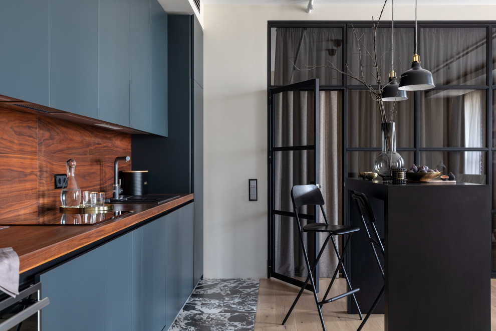 Modern inredning av ett mellanstort brun linjärt brunt kök och matrum, med en enkel diskho, svarta skåp, träbänkskiva, brunt stänkskydd, stänkskydd i trä, integrerade vitvaror och en köksö