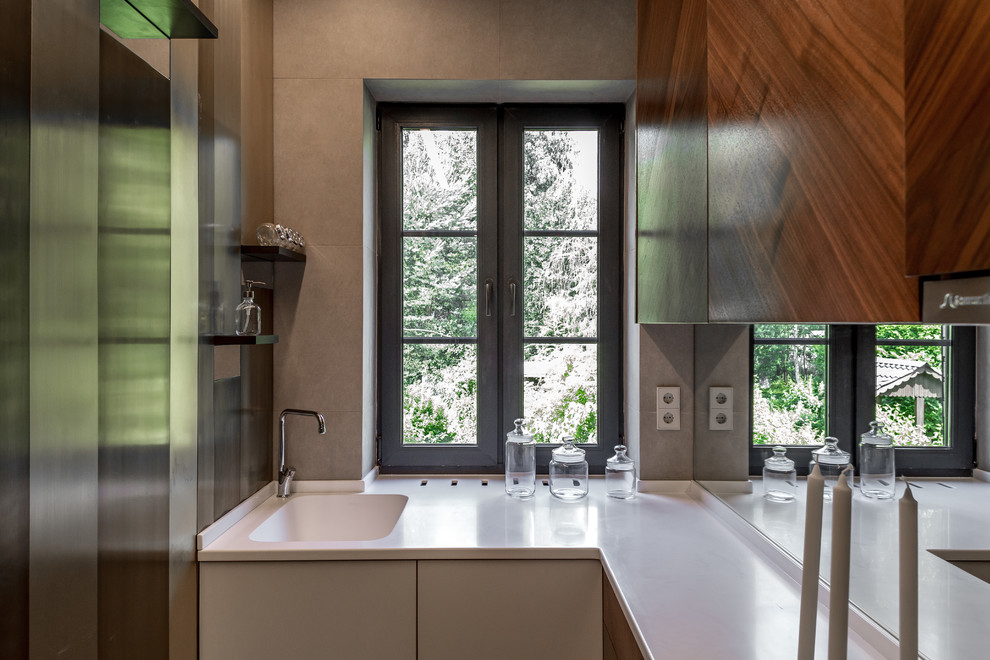 На фото: отдельная, угловая кухня в современном стиле с монолитной мойкой, плоскими фасадами, белыми фасадами и фартуком из стекла