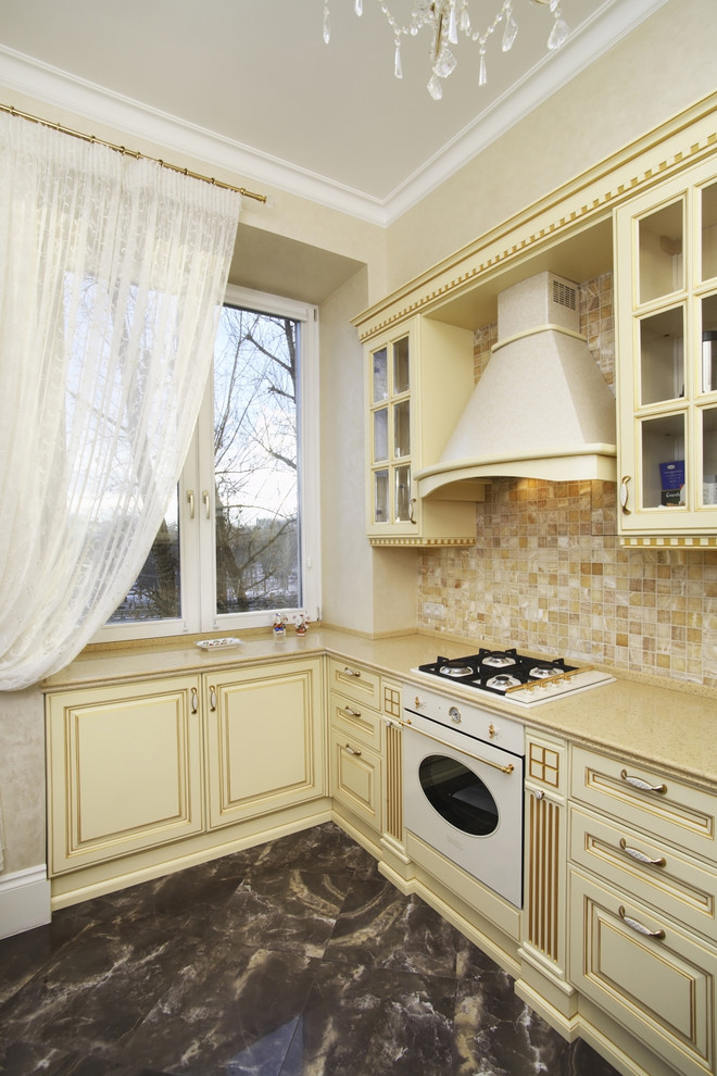 На фото: отдельная, п-образная кухня в классическом стиле с фасадами с выступающей филенкой, бежевыми фасадами, бежевым фартуком и белой техникой