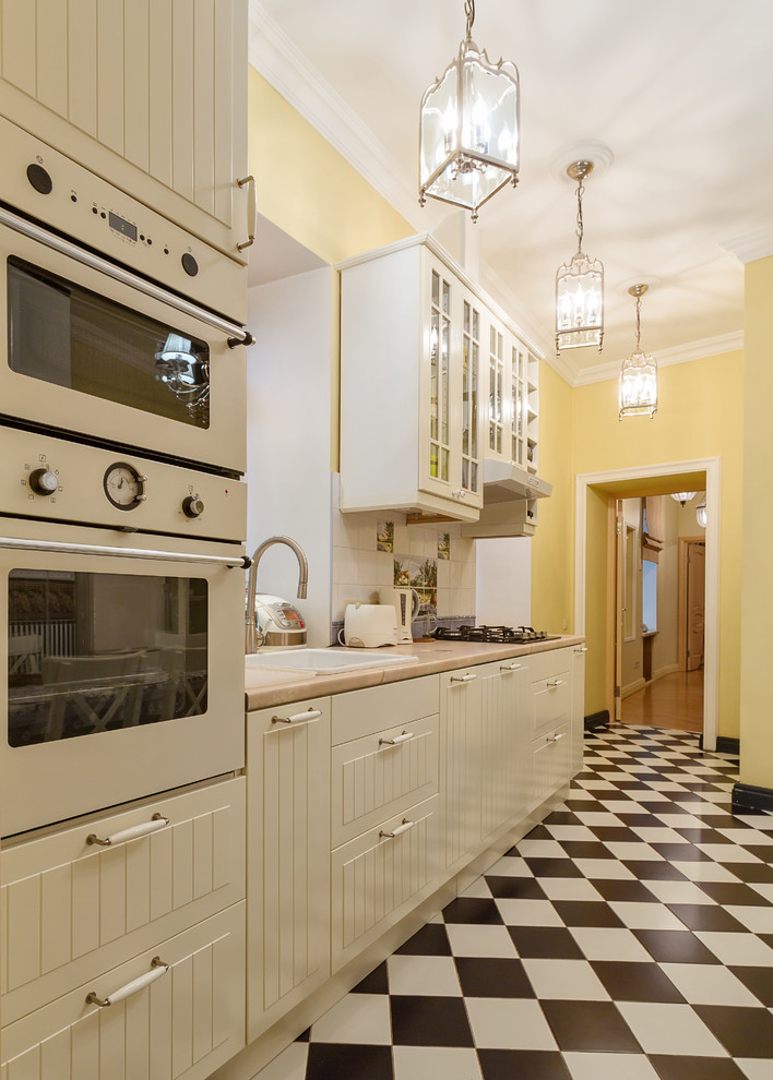 Стильный дизайн: отдельная, прямая кухня в классическом стиле с накладной мойкой, белыми фасадами, белым фартуком и белой техникой без острова - последний тренд