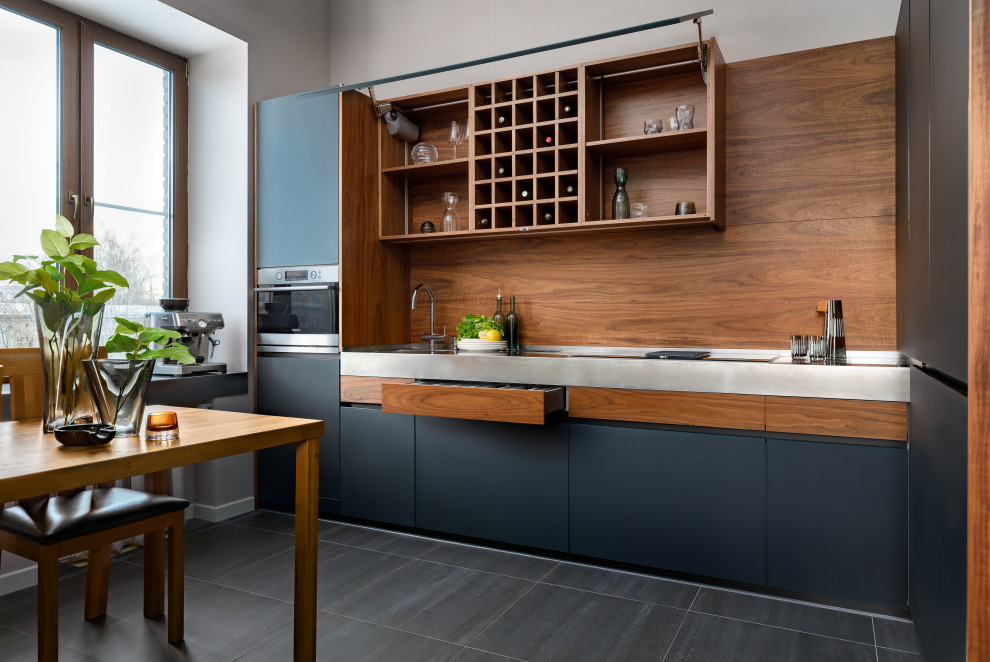 This is an example of a medium sized contemporary l-shaped kitchen/diner in Moscow with a single-bowl sink, black cabinets, stainless steel worktops, brown splashback, wood splashback, integrated appliances, no island and grey worktops.
