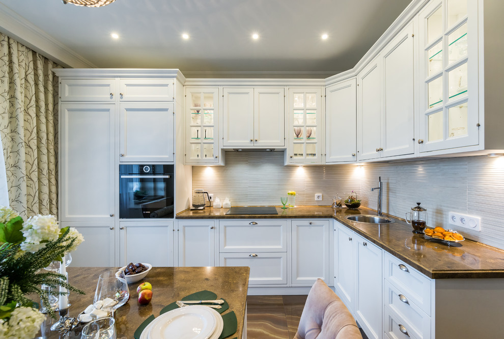 Inspiration for a classic l-shaped enclosed kitchen in Moscow with a built-in sink, recessed-panel cabinets, white cabinets, white splashback, no island and brown floors.