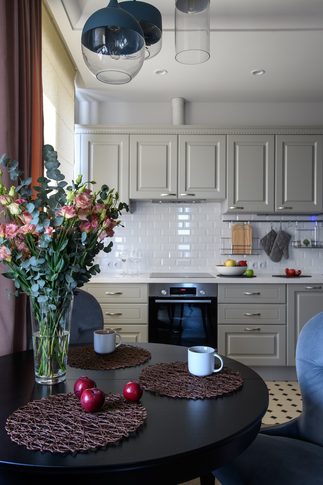 Foto på ett mellanstort skandinaviskt vit linjärt kök med öppen planlösning, med en enkel diskho, luckor med upphöjd panel, grå skåp, bänkskiva i koppar, vitt stänkskydd, stänkskydd i keramik, svarta vitvaror, klinkergolv i keramik och beiget golv