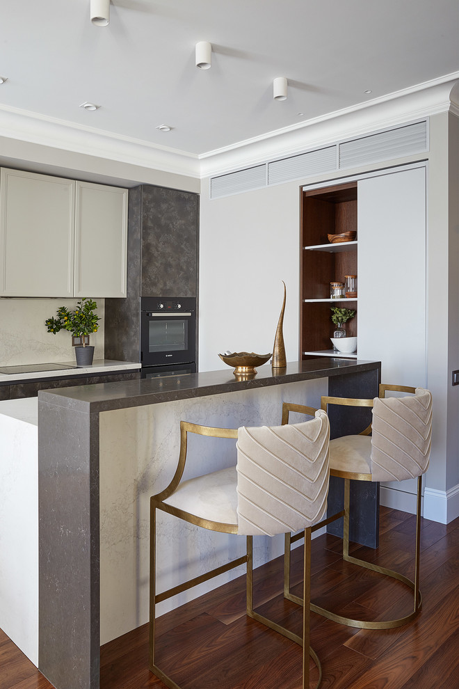 Immagine di un cucina con isola centrale minimal con ante beige, paraspruzzi beige, elettrodomestici neri, pavimento in legno massello medio e top bianco
