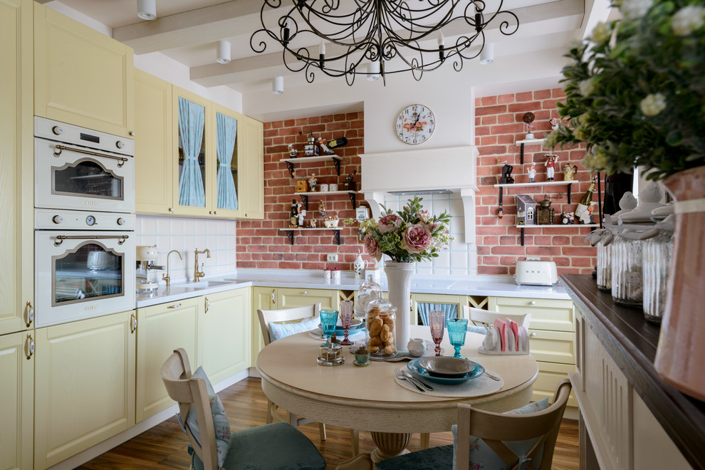 На фото: кухня в стиле лофт с желтыми фасадами и фартуком из кирпича