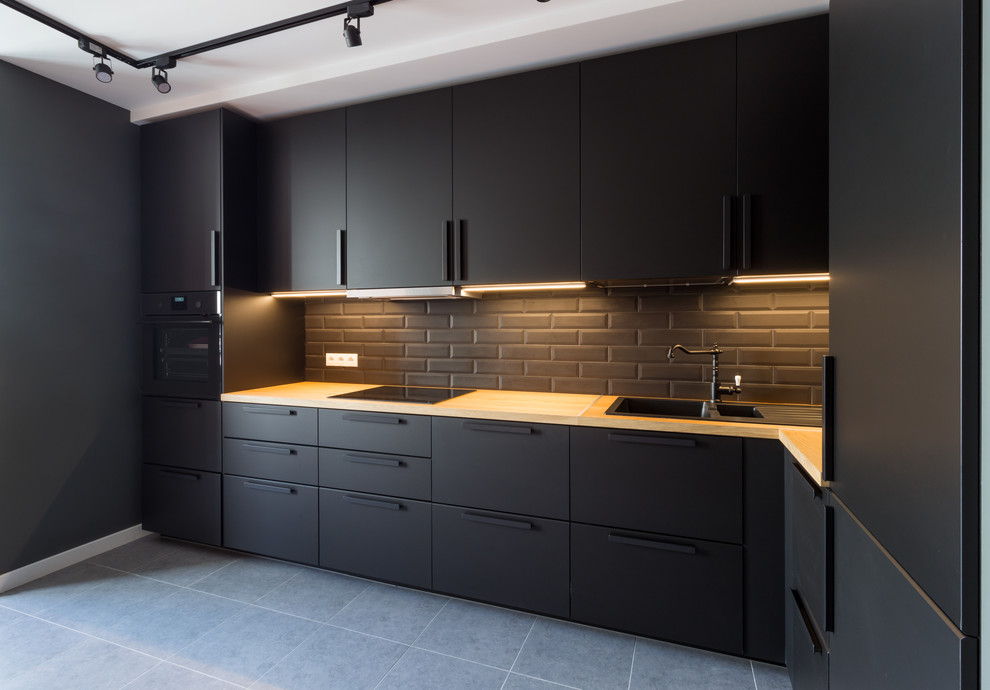 Contemporary l-shaped kitchen in Saint Petersburg with flat-panel cabinets, black cabinets, metro tiled splashback, black appliances, no island, grey floors, beige worktops, a double-bowl sink and black splashback.